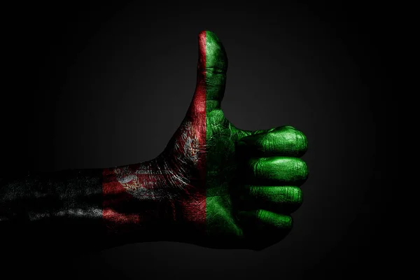 一只手拿着一个绘制的达吉斯坦国旗，上面写着一个手指上的标志，象征着成功，准备，在黑暗的背景上完成的任务. — 图库照片