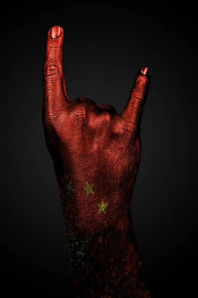 En hånd med en trukket porcelæn flag viser et gedetegn, et symbol på mainstream, metal og rockmusik, på en mørk baggrund - Stock-foto