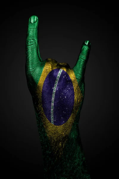 Una mano con la bandera pintada de Brasil muestra un signo OK sobre un fondo oscuro . — Foto de Stock