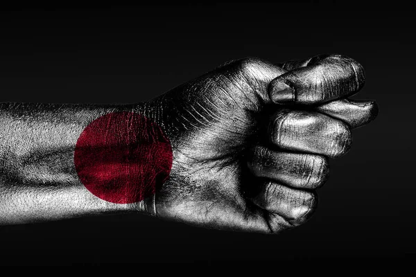 Una mano con una bandera de Japón pintada muestra un higo, un signo de agresión, desacuerdo, una disputa sobre un fondo oscuro . —  Fotos de Stock