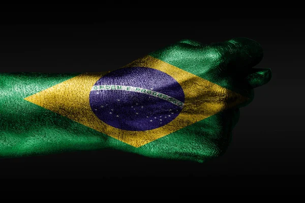 Рука с раскрашенным флагом Бразилии показывает фиг, знак агрессии, разногласия, спор на тёмном фоне . — стоковое фото