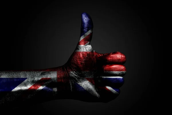 Eine Hand mit einer gezogenen großen britischen Flagge zeigt ein Zeichen mit dem Finger nach oben, ein Symbol für Erfolg, Bereitschaft, eine Aufgabe, die auf einem dunklen Hintergrund erledigt wird. — Stockfoto