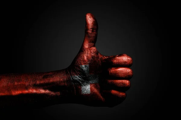 Una mano con una bandiera disegnata della Svizzera mostra un dito in su, un simbolo di successo, prontezza, un compito fatto su uno sfondo scuro . — Foto Stock