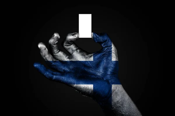 Mão com uma bandeira pintada Finlândia segurando uma pequena folha branca com espaço para uma inscrição, mock up — Fotografia de Stock