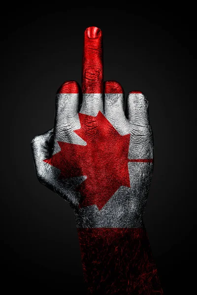 Kanada boyalı bayrağı olan bir el, karanlık bir arka plana karşı orta parmağı, saldırganlık belirtisini gösterir. — Stok fotoğraf
