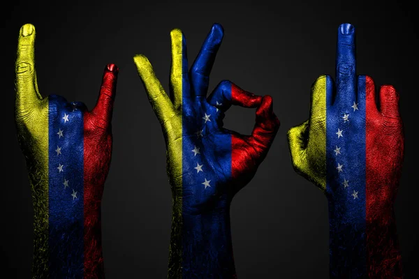 Un conjunto de tres manos con una bandera pintada Venezuela mostrar el dedo medio, cabra y bien, un signo de agresión, protesta y aprobación sobre un fondo oscuro . — Foto de Stock