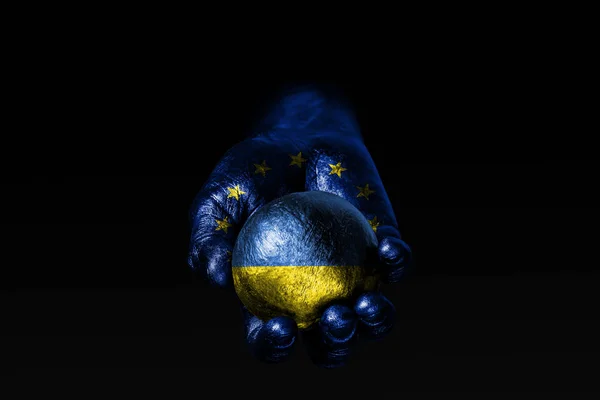 Рука з намальований прапор ЄС тримає м'яч з намальований прапор України, ознакою впливу, тиску або збереження і захисту. — стокове фото