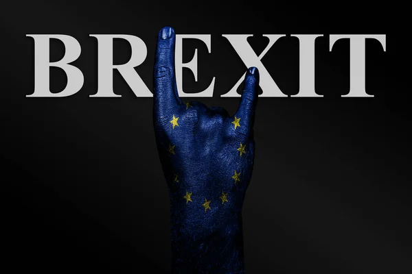 Sobre un fondo oscuro, una mano con una bandera de la UE pintada y la palabra BREXIT muestra un signo de cabra, un símbolo de la música mainstream, metal y rock . —  Fotos de Stock