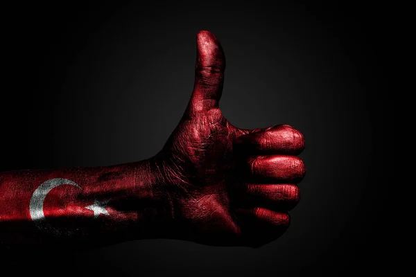Une main avec un drapeau de Turquie dessiné montre un signe du doigt vers le haut, un symbole de succès, de préparation, une tâche effectuée sur un fond sombre . — Photo