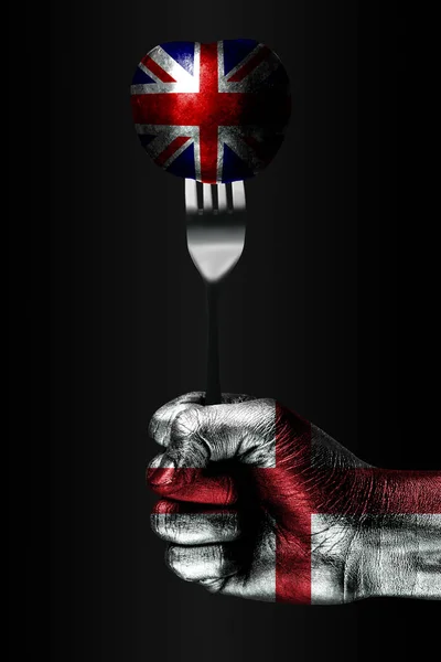 Ruka s nakreslené vlajkou Anglie má vidličku, na které je koule s nakreslená vlajka Velké Británie, známka vlivu, tlaku, sevření a anekxie. — Stock fotografie
