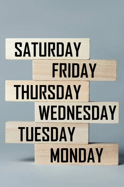 List of wooden blocks lying on top of each other with a list of days of the six-day working week in English. Vertical frame