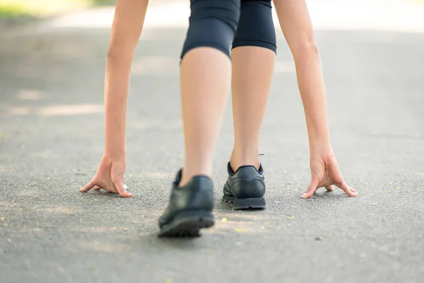 Женские ноги и руки поставлены на асфальт крупным планом, символом старта перед бегом, сильной личностью и марафоном — стоковое фото