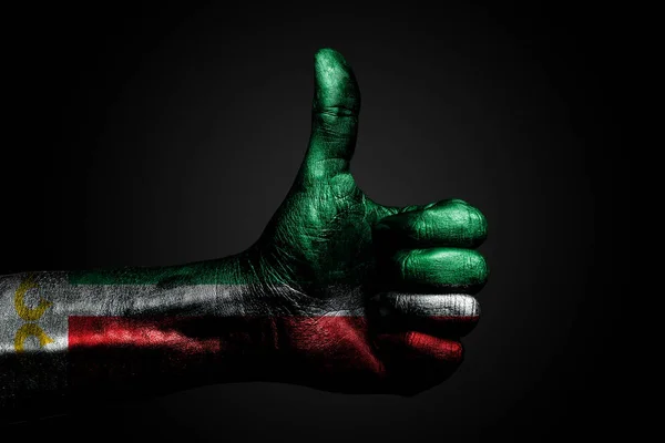 Eine Hand mit einer gezogenen tschetschenischen Flagge zeigt ein Zeichen des Erhobenen Fingers, ein Symbol für Erfolg, Bereitschaft, eine Aufgabe, die auf einem dunklen Hintergrund erledigt wird. — Stockfoto