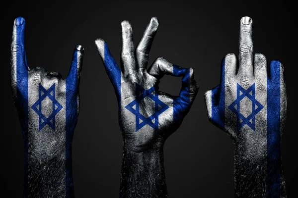 Un conjunto de tres manos con una bandera pintada Israel mostrar el dedo medio, cabra y bien, un signo de agresión, protesta y aprobación sobre un fondo oscuro . —  Fotos de Stock