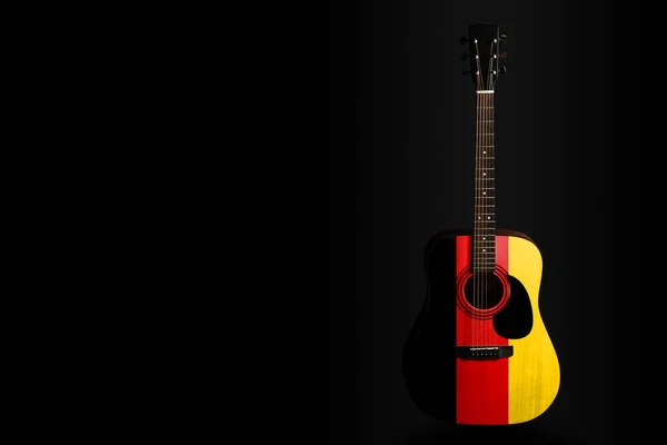 Acoustic concert guitar with a drawn flag Germany, on a dark background, as a symbol of national creativity or folk song.