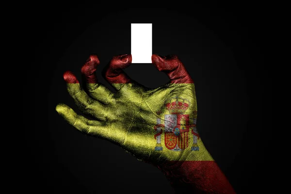 Рука с раскрашенным флагом Испания держит небольшой белый лист с местом для надписи, макет — стоковое фото