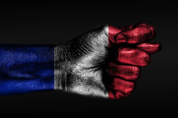 Eine Hand mit einer bemalten Frankreich-Flagge zeigt eine Feige, ein Zeichen von Aggression, Uneinigkeit, Streit auf dunklem Hintergrund. — Stockfoto