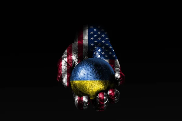 A hand with a drawn USA flag holds a ball with a drawn Ukraine flag, a sign of influence, pressure or conservation and protection.