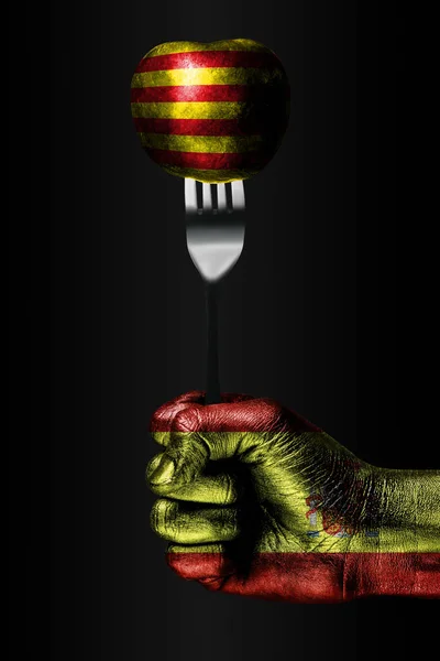 Une main avec un drapeau d'Espagne dessiné tient une fourchette, sur laquelle se trouve une balle avec un drapeau de Catalogne dessiné, un signe d'influence, de pression, d'adhérence et d'anecxie . — Photo