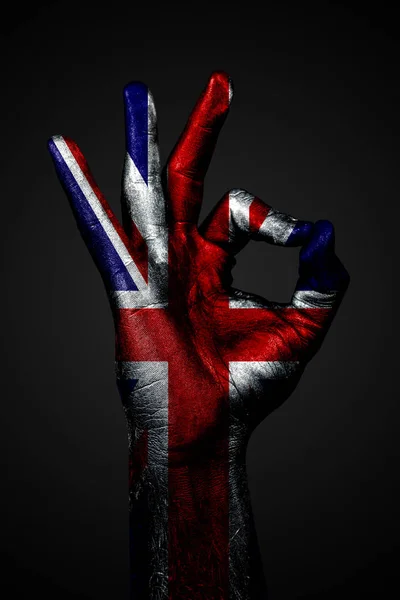 Eine Hand mit der bemalten Flagge von uk zeigt ein Ok-Zeichen auf dunklem Hintergrund — Stockfoto