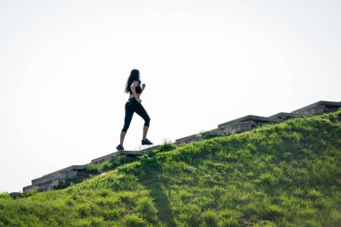Koyu saçlı ince güzel kız merdivenlerden yukarı çalışır, sağlıklı yaşam tarzı sembolü, güçlü bir lider ve sağlıklı rekabet