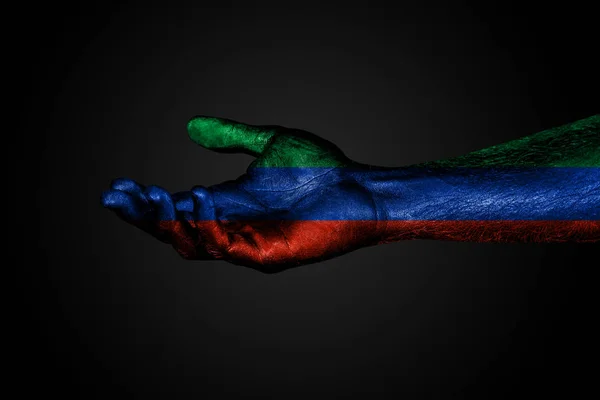 Uma mão estendida com uma bandeira pintada de Daguestão, um sinal de ajuda ou um pedido, em um fundo escuro — Fotografia de Stock