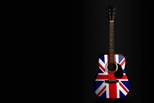 Akustisk konsert gitarr med en dragen flagga Storbritannien, på en mörk bakgrund, som en symbol för nationell kreativitet eller folksång. — Stockfoto