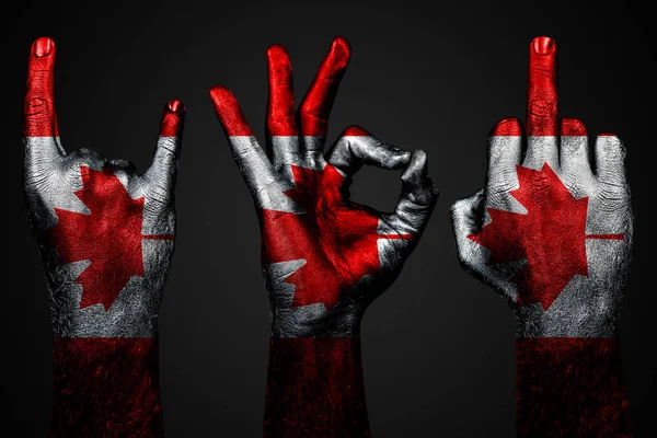 Um conjunto de três mãos com uma bandeira pintada Canadá mostrar dedo médio, cabra e Ok, um sinal de agressão, protesto e aprovação em um fundo escuro . — Fotografia de Stock