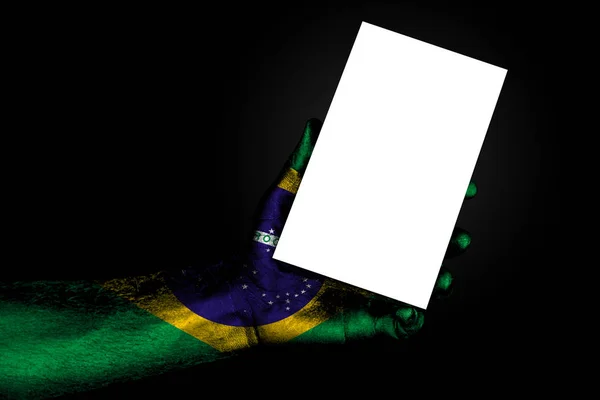 Mão com bandeira pintada Brasil segurando uma grande folha branca com espaço para uma inscrição, mock up — Fotografia de Stock