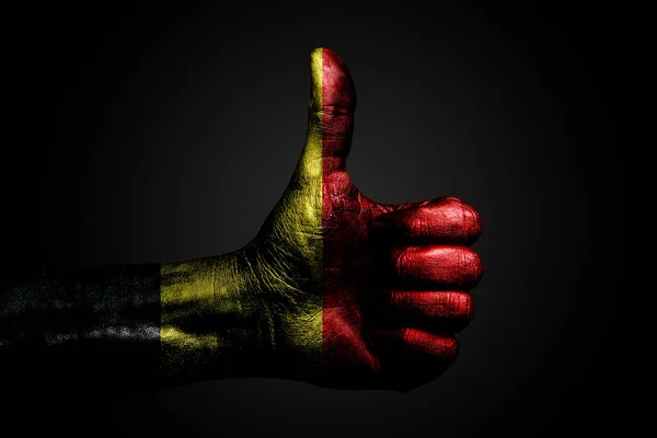 A hand with a drawn Belgium flag shows a finger up sign, a symbol of success, readiness, a task done on a dark background. — Stock Photo, Image