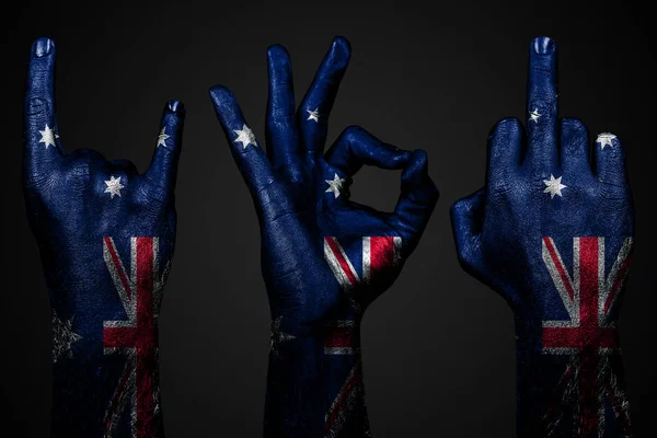 Un insieme di tre mani con una bandiera dipinta Australia mostrano dito medio, capra e Ok, un segno di aggressione, protesta e approvazione su uno sfondo scuro . — Foto Stock
