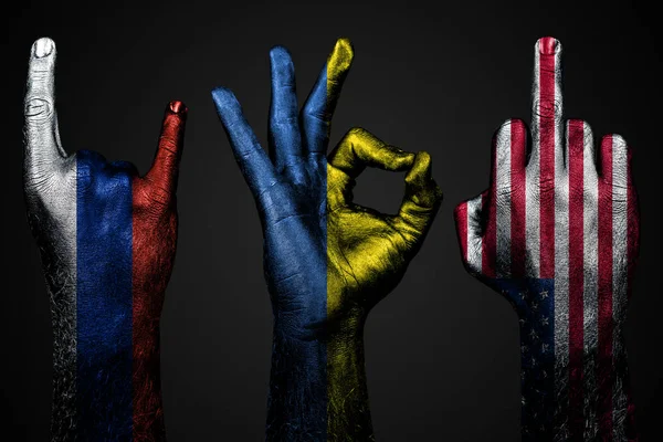 Egy sor három kéz egy festett zászló Ukrajna, Oroszország és az USA show középső ujj, kecske-és Oké, a jele az agresszió, a tiltakozás és jóváhagyás sötét háttér. — Stock Fotó
