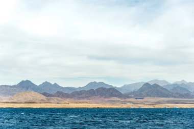 Deniz manzarası, arka planda yüksek kel Dağları ile mavi deniz görünümü
