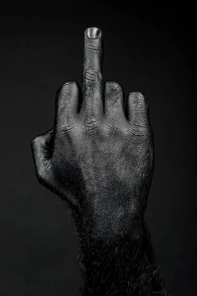 full black hand showing middle finger on black background
