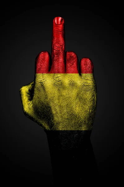 Een hand met een geschilderde vlag van België toont de middelvinger, een teken van agressie, tegen een donkere achtergrond. — Stockfoto