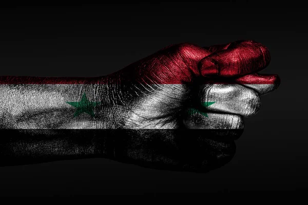 Una mano con una bandera siria pintada muestra un higo, un signo de agresión, desacuerdo, una disputa sobre un fondo oscuro . —  Fotos de Stock
