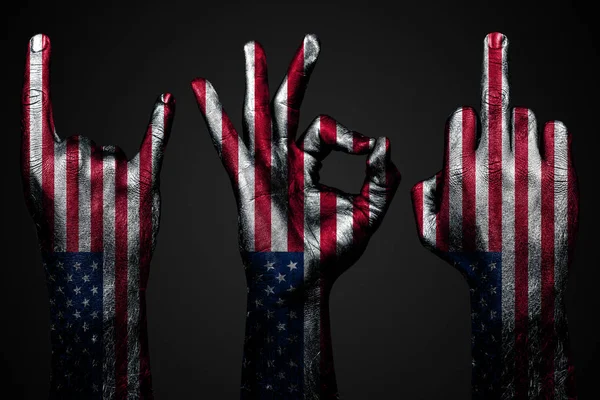 Um conjunto de três mãos com uma bandeira pintada EUA mostram dedo médio, cabra e Ok, um sinal de agressão, protesto e aprovação em um fundo escuro . — Fotografia de Stock