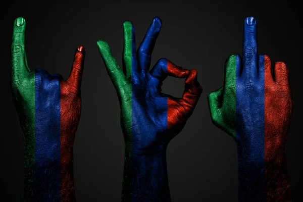 Egy sor három kéz egy festett zászló Dagestan show középső ujj, kecske-és Oké, a jele az agresszió, a tiltakozás és jóváhagyás sötét háttér. — Stock Fotó
