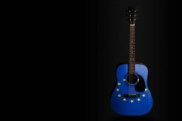 Acoustic concert guitar with a drawn flag EU, on a dark background, as a symbol of national creativity or folk song.