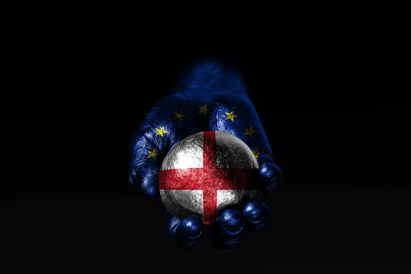 Una mano con una bandera de la UE dibujada sostiene una pelota con una bandera de Inglaterra dibujada, un signo de influencia, presión o conservación y protección . —  Fotos de Stock