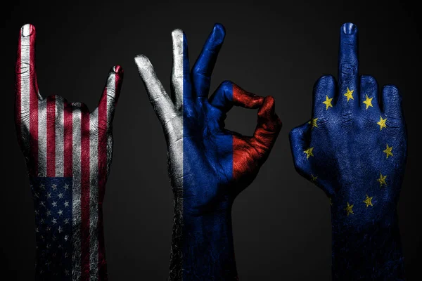 Un ensemble de trois mains avec un drapeau peint des États-Unis, l'Union européenne et la Russie montrent majeur, chèvre et Ok, un signe d'agression, de protestation et d'approbation sur un fond sombre . — Photo