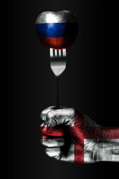 Рука з намальованої Англії прапор тримає виделкою, на якій знаходиться кулька з намальований прапором Росії, ознакою впливу, тиску, зчеплення і anecxia. — стокове фото