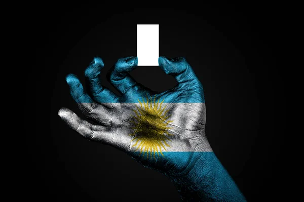 Mão com uma bandeira pintada Argentina segurando uma pequena folha branca com espaço para uma inscrição, mock up — Fotografia de Stock