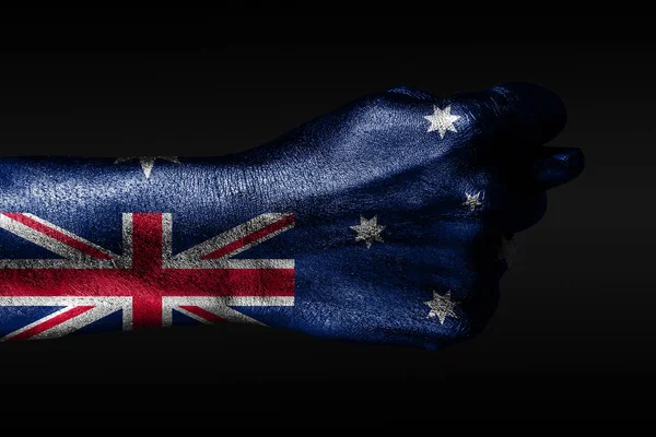 Una mano con una bandera de Australia pintada muestra un higo, un signo de agresión, desacuerdo, una disputa sobre un fondo oscuro . — Foto de Stock