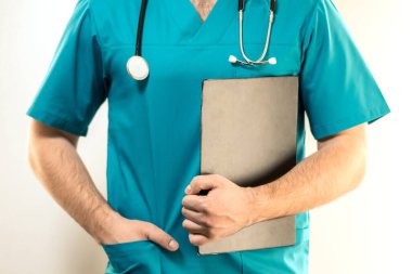 Omuzlarında steteskopla genç bir erkek doktor siyah bir klasör tutuyor..