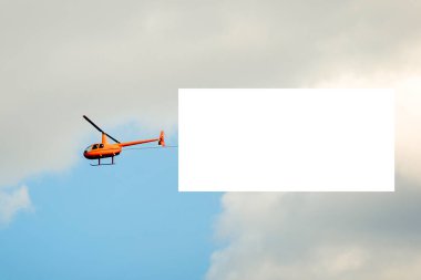 Sarı helikopter gökyüzünde, altında beyaz bir tuval var..