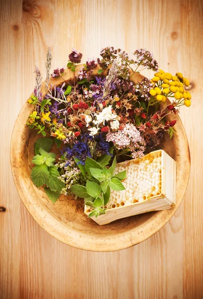 Medicinal and healing herbs and flowers in a wooden bowl on rustic table