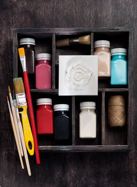 Brushes, paints for drawing, plaster bas-relief in a wooden box of the artist decorator, flat lay. Set for drawing and creativity
