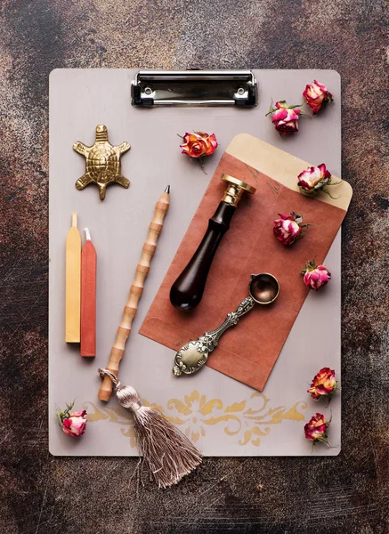 Retro  Clipboard with wax seal, sealing wax and envelope on a dark background, flat lay.