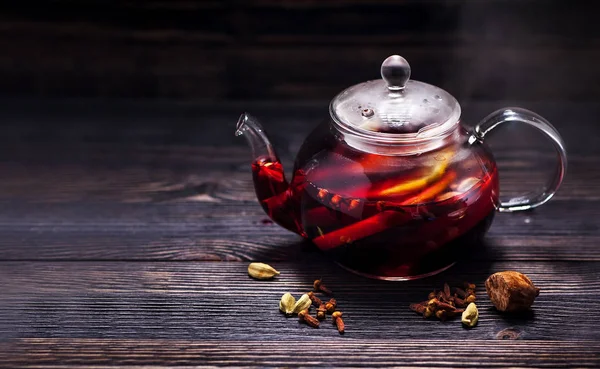 Hot wine mulled wine with spices in a glass teapot on a wooden table and space for text. Winter CHRISTMAS HOT DRINK